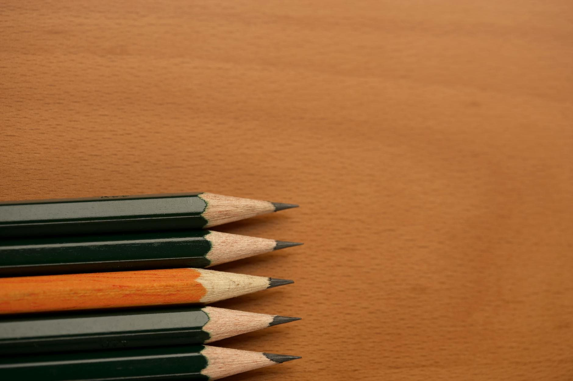 Sharpened pencils aligned on a wooden surface with visible lead tips.
