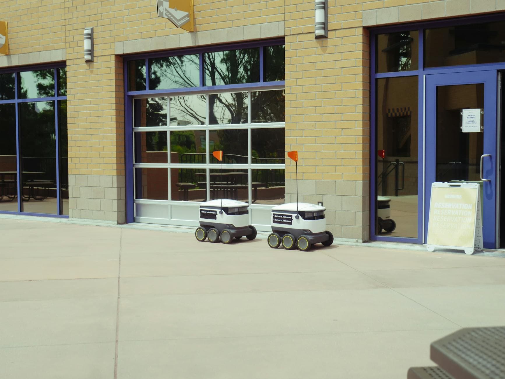 Two autonomous delivery robots navigate an outdoor space, showcasing modern technology and innovation.