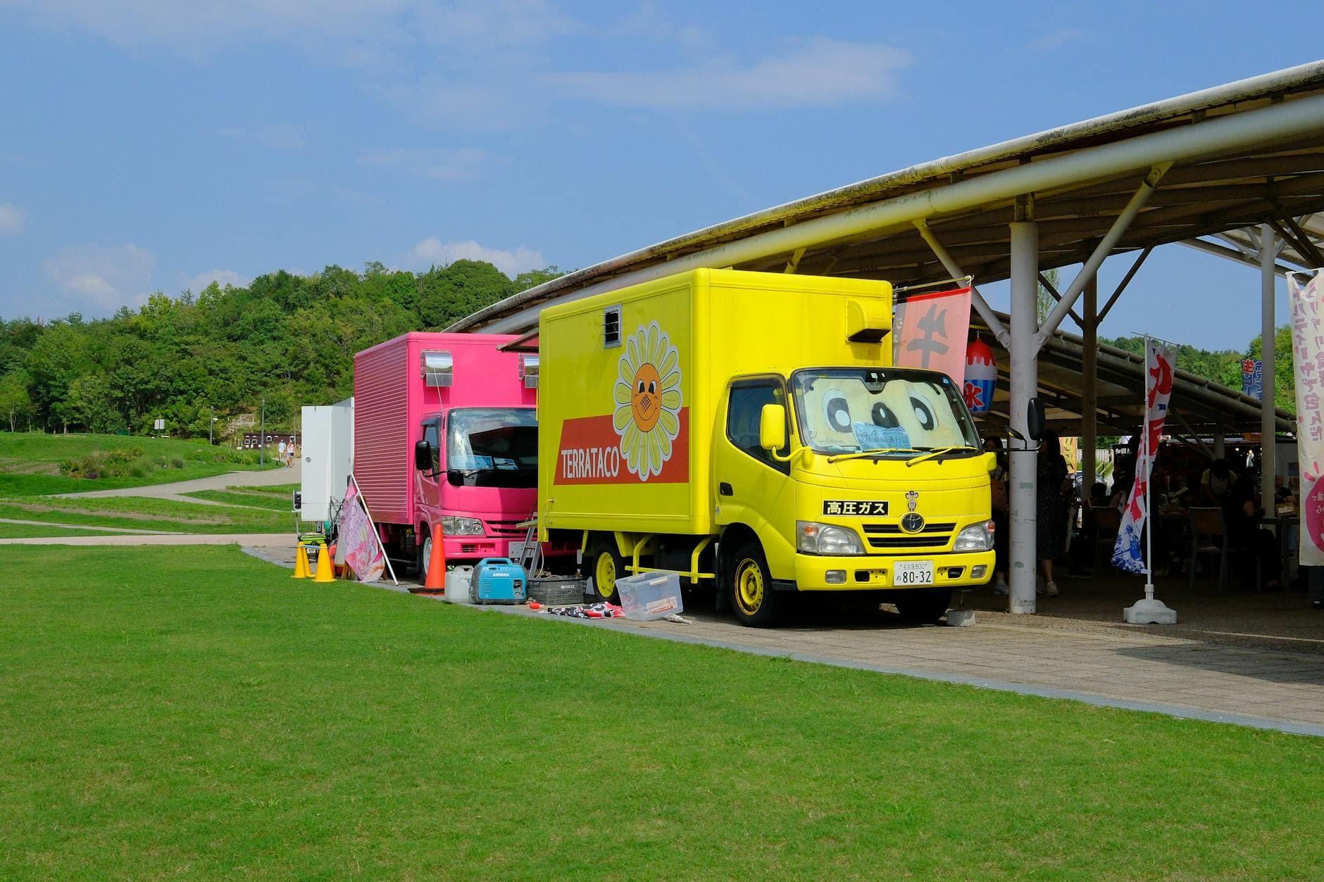Colorful food trucks parked in a lively outdoor park in Nagoya, Japan during summer.