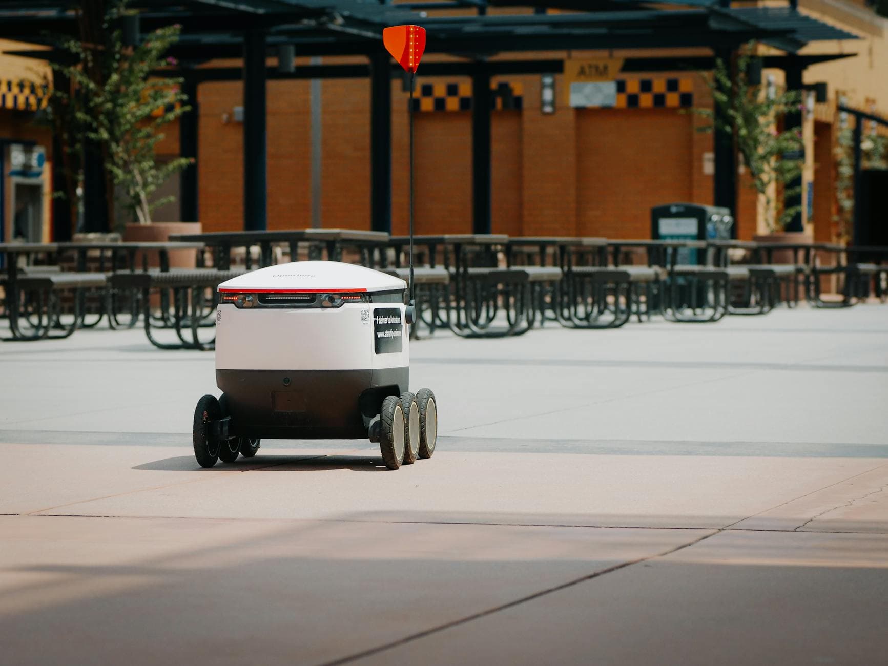 Futuristic delivery robot navigating an empty outdoor plaza, symbolizing modern innovation and mobility.