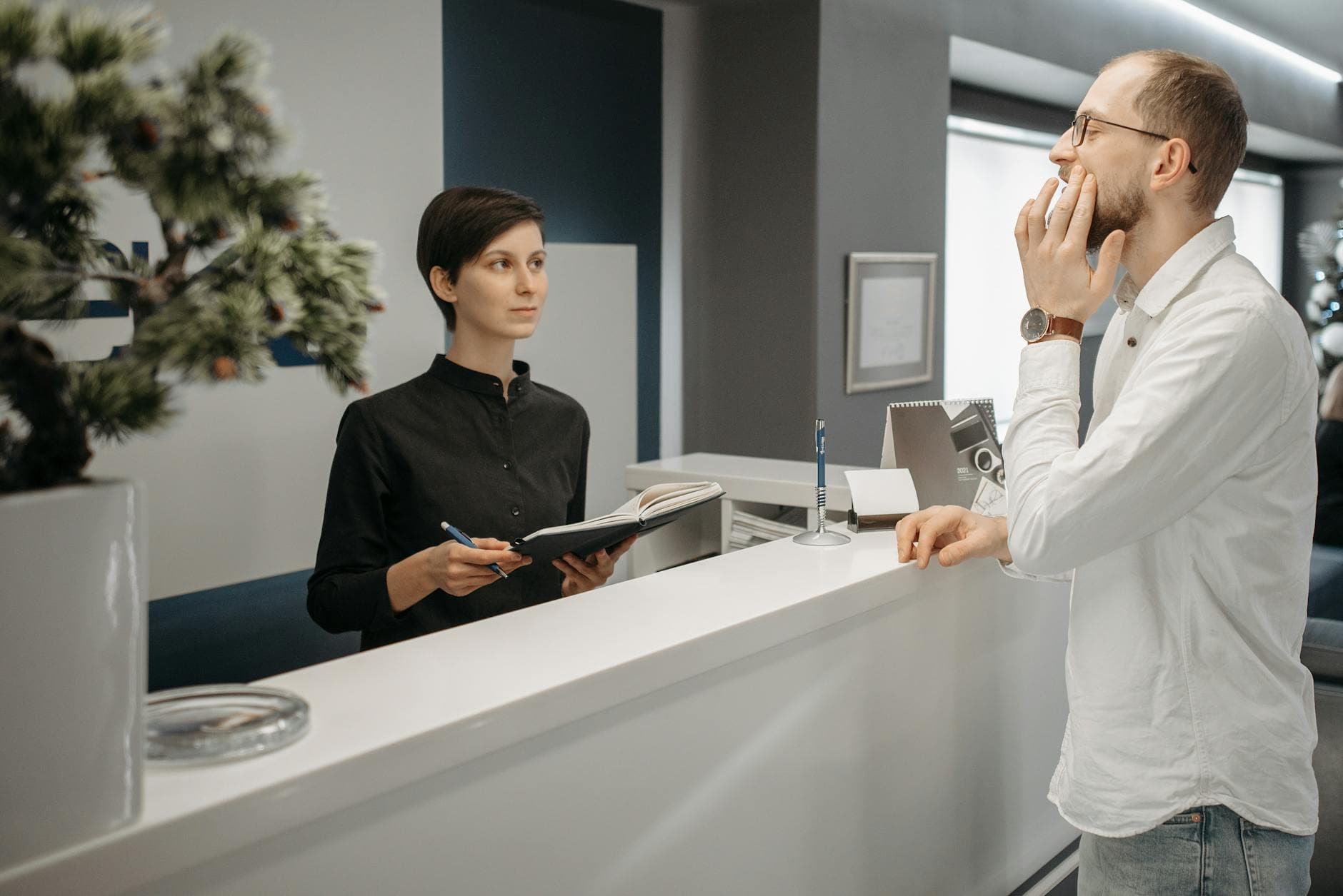 A receptionist assists a patient with a toothache at a dental clinic's front desk.