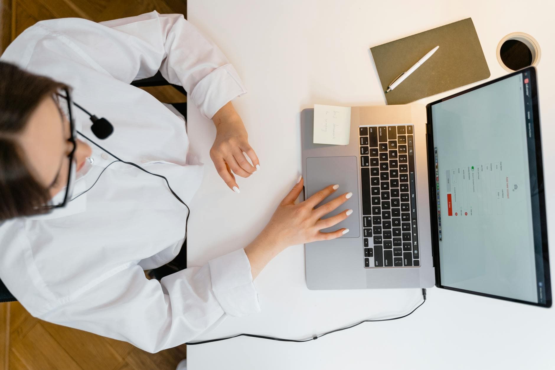 A call center agent wearing a headset works on her laptop in a bright, modern office.